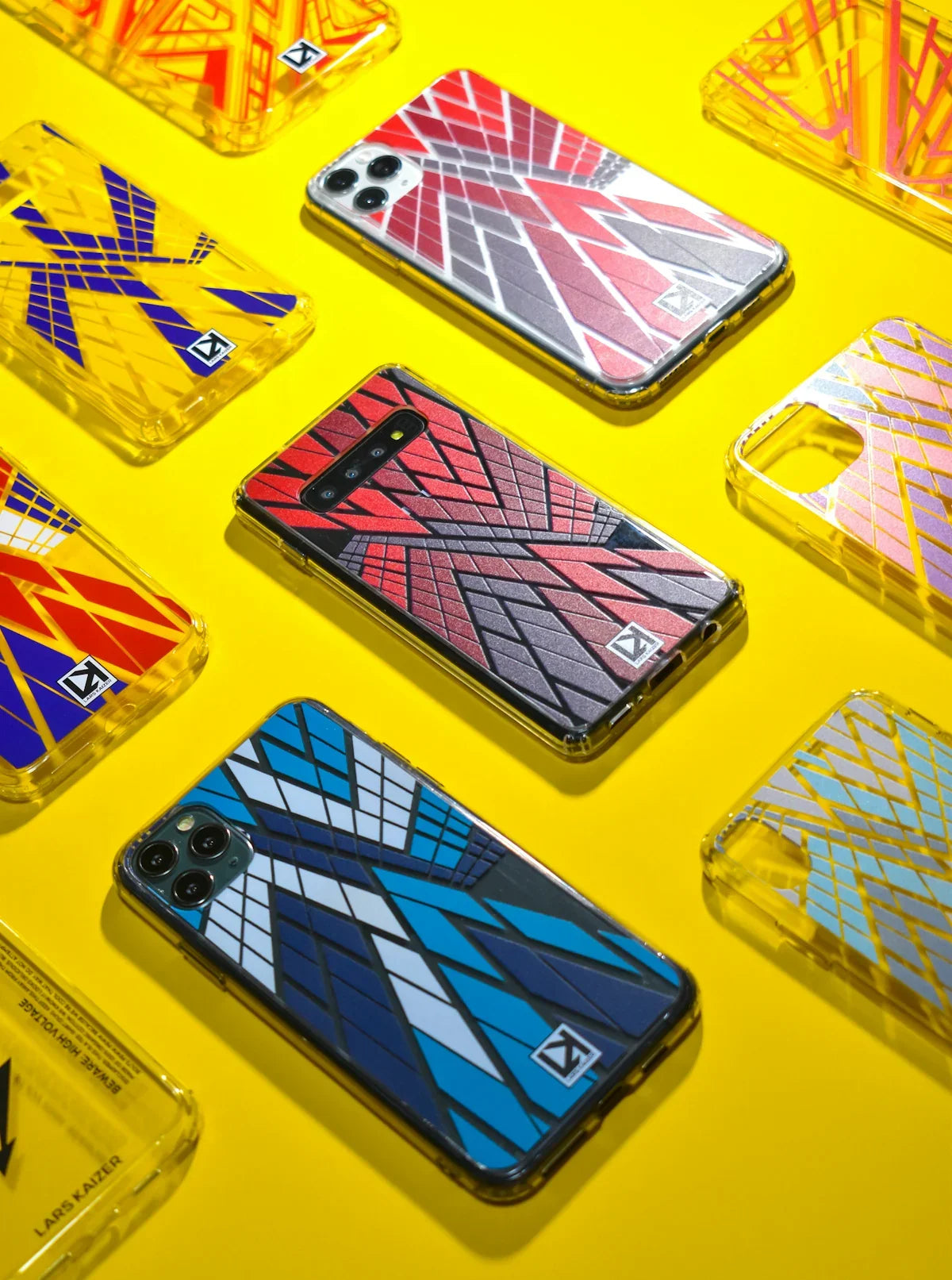 Renkli geometrik desenli iPhone ve Samsung telefon kılıfları, sarı arka plan üzerinde.