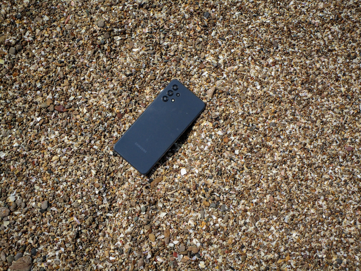 a cell phone laying on the ground covered in sand