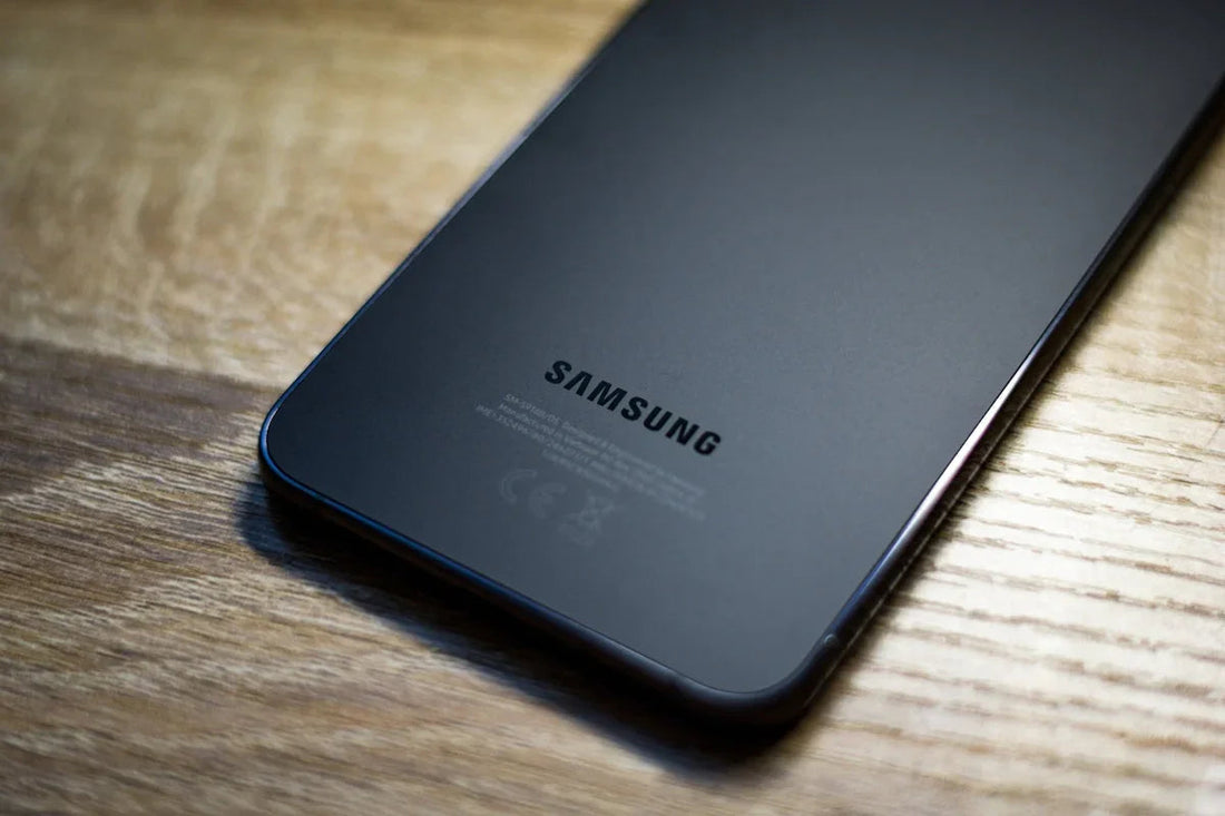 Ahşap zeminde yatan siyah Samsung akıllı telefonun arka yüzü