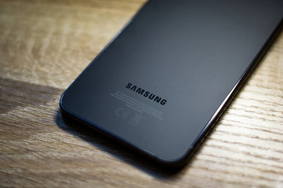 Ahşap zeminde yatan siyah Samsung akıllı telefonun arka yüzü